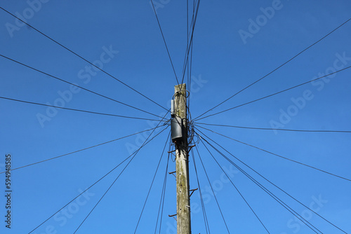 Wooden telegraph pole with wires leading off at angles against blue sky