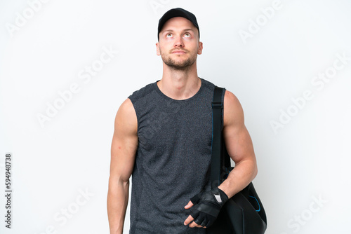 Young blonde sport caucasian man with sport bag over isolated white background and looking up © luismolinero