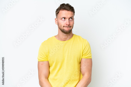 Young blonde caucasian man isolated on white background having doubts while looking up