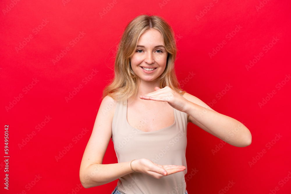 Young English woman isolated on red background holding copyspace imaginary on the palm to insert an ad Young English woman isolated on red background holding copyspace imaginary on the palm to insert an ad