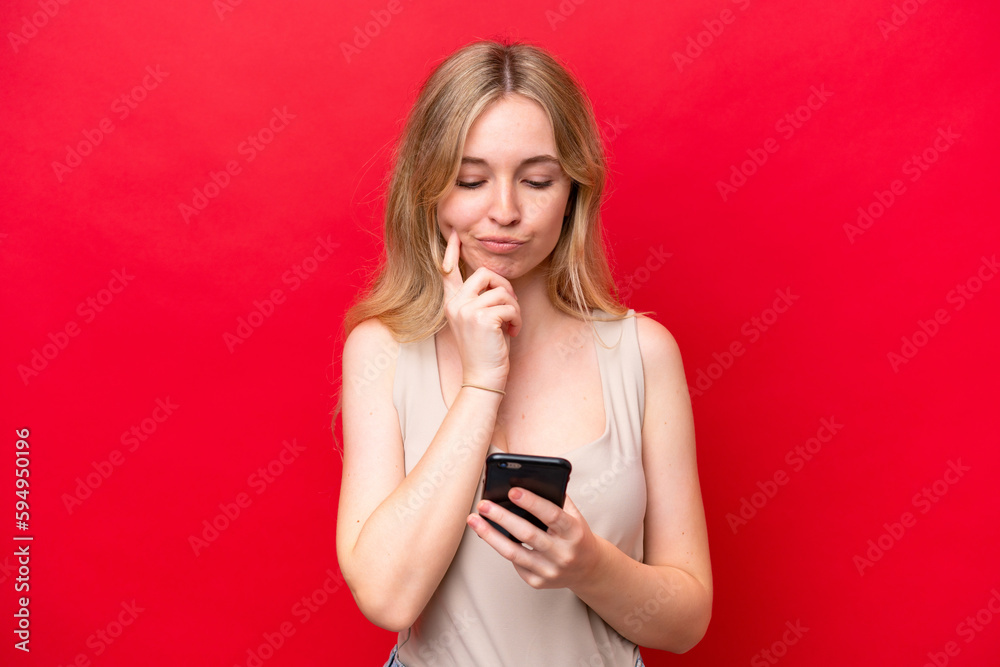 Young English woman isolated on red background thinking and sending a message Young English woman isolated on red background thinking and sending a message