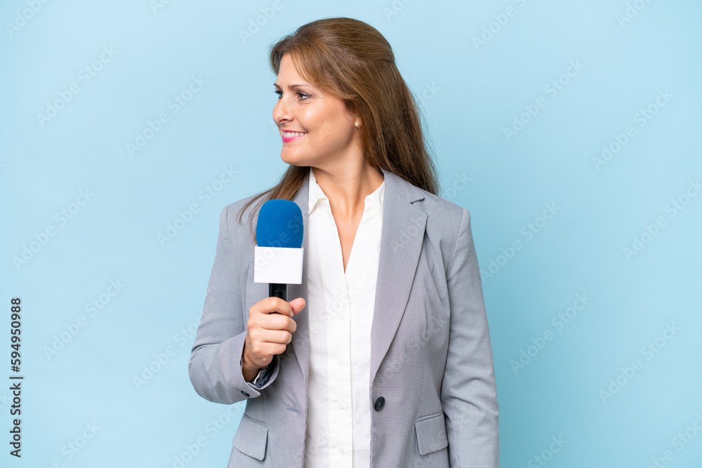 Middle-aged TV presenter woman over isolated blue background looking side Middle-aged TV presenter woman over isolated blue background looking side