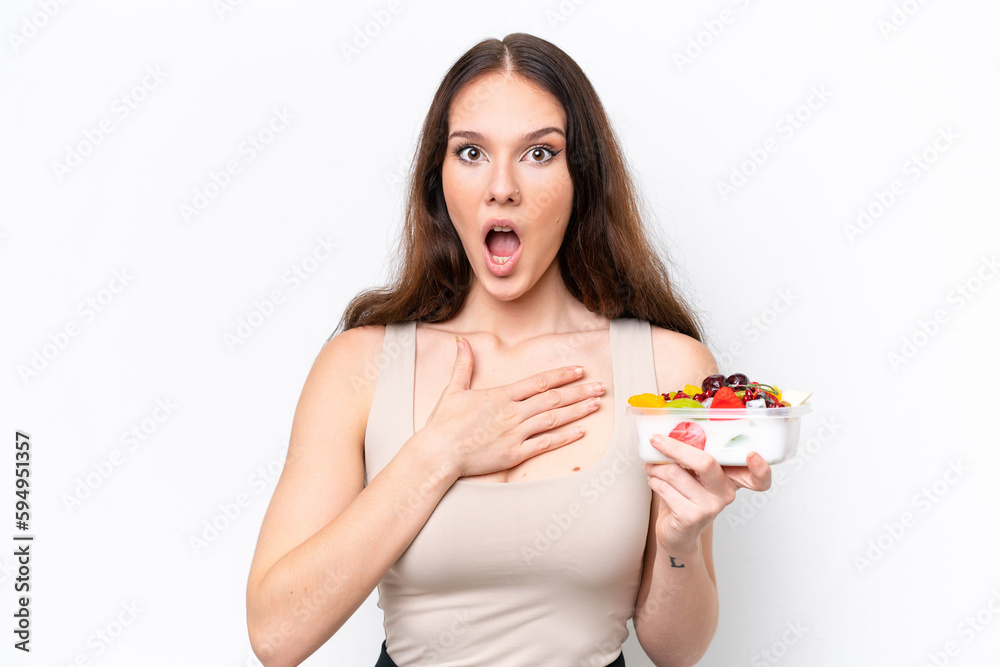Young caucasian woman holding a bowl of fruit isolated on white background surprised and shocked while looking right Young caucasian woman holding a bowl of fruit isolated on white background surprised and shocked while looking right