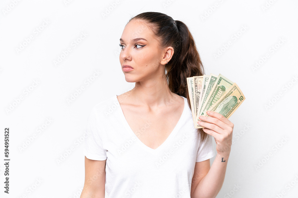 Young caucasian woman taking a lot of money isolated on white background looking to the side Young caucasian woman taking a lot of money isolated on white background looking to the side