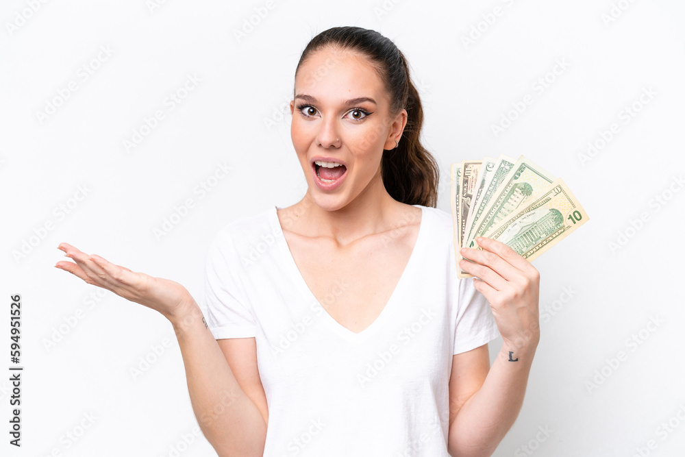 Young caucasian woman taking a lot of money isolated on white background with shocked facial expression Young caucasian woman taking a lot of money isolated on white background with shocked facial expression