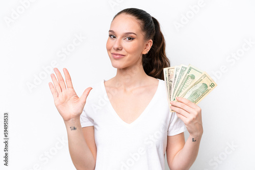 Young caucasian woman taking a lot of money isolated on white background counting five with fingers