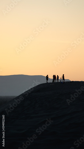Group of people standing atop a grassy hill, surrounded by trees, while looking out into the horizon © Luis Perez/Wirestock Creators