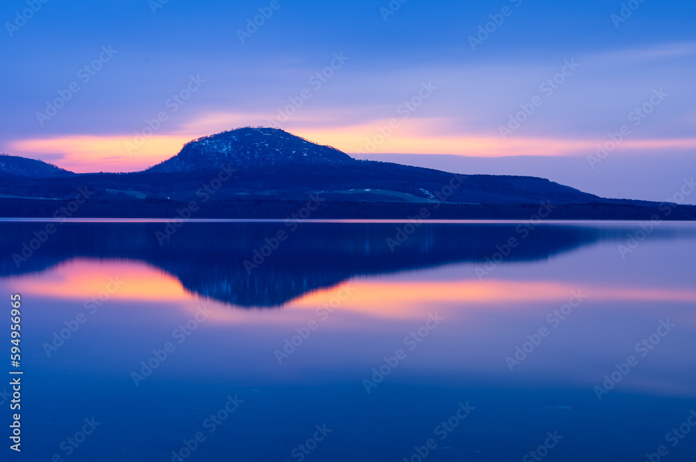 夜明けの空を湖面に反射する湖。北海道の屈斜路湖。