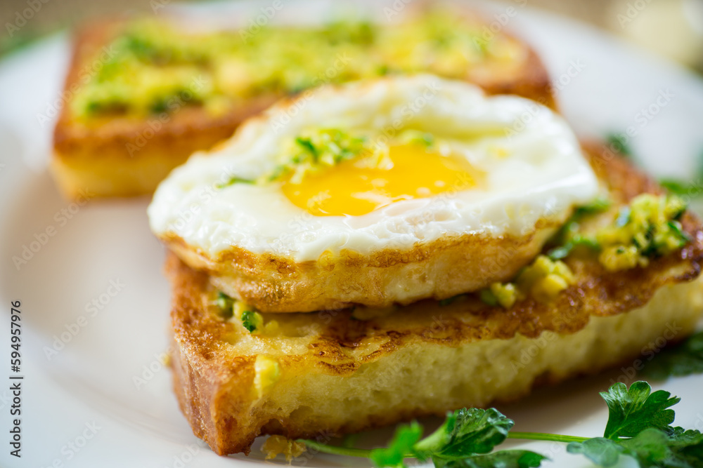 Fried croutons in batter with garlic and herbs and a fried egg in a plate.