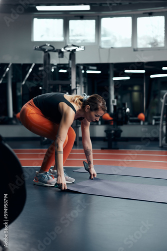 Fototapeta Naklejka Na Ścianę i Meble -  Pretty woman working out and stretching in a gym.