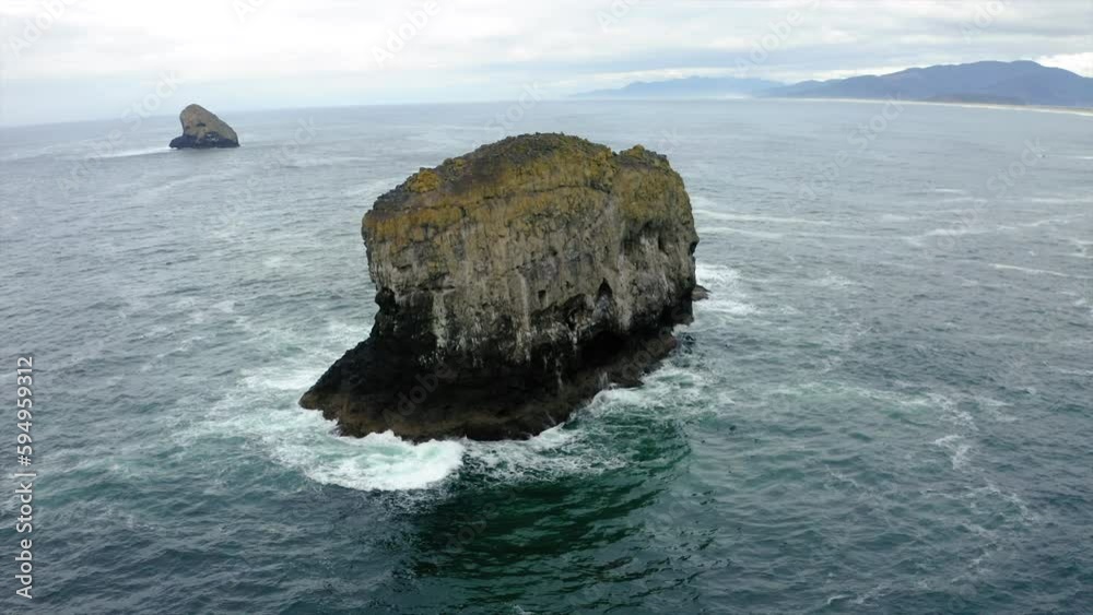 Drone view over huge rocks in the ocean under a cloudy sky Drone view over huge rocks in the ocean under a cloudy sky