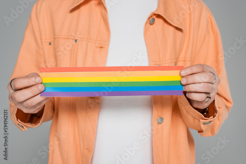 Cropped view of gay man holding lgbt flag isolated on grey.