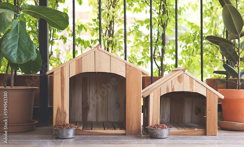 Schilderij op canvas two empty wooden dog's houses with dog food bowls  in balcony decorated with houseplant in plant pots
