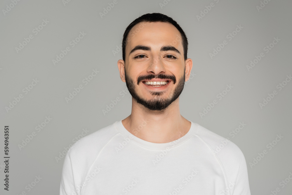 Portrait of smiling gay man in white t-shirt looking at camera isolated on grey. Portrait of smiling gay man in white t-shirt looking at camera isolated on grey.