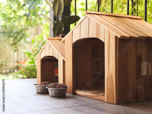 two empty wooden dog's houses with dog food bowls  in balcony decorated with houseplant in plant pots.