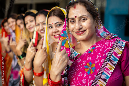  Election in india. Group of happy traditional indian women standing in queue showing their finger marked with black ink after casting vote. 