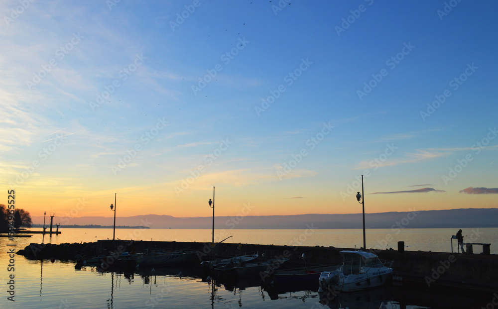 Lake Geneva at sunset, wooden pier on big lake in Evian Lake Geneva at sunset, wooden pier on big lake in Evian