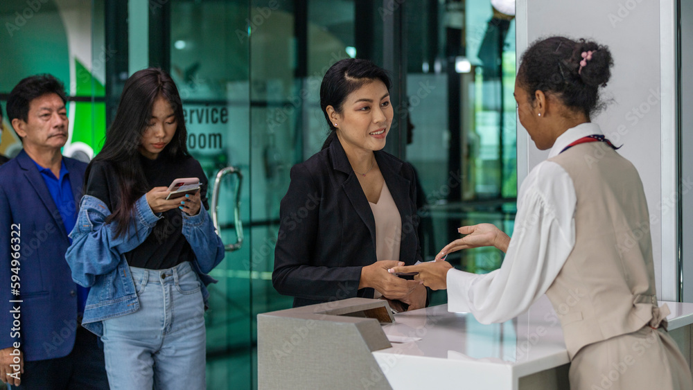 Young female airline stewardess or ground staff checks documents with passenger before taking flight at an airport counter. Security check at boarding counter. Young female airline stewardess or ground staff checks documents with passenger before taking flight at an airport counter. Security check at boarding counter.