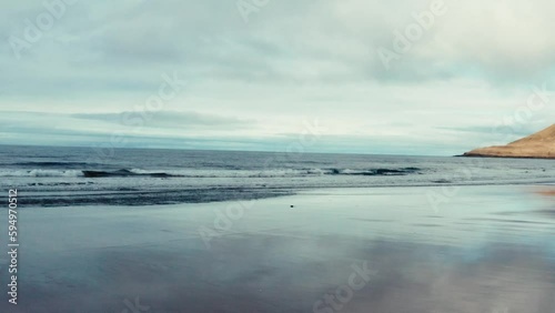 Waves on black beach in front of beautiful Icelandic coastline