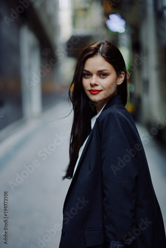 Fashion woman smile with teeth portrait looking at camera tourist in stylish clothes in jacket with red lips walking down narrow city street flying hair, travel, cinematic color, retro vintage style. © SHOTPRIME STUDIO