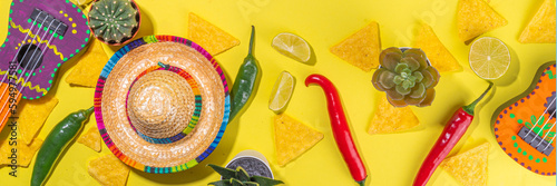 Mexican Cinco de Mayo holiday background with mexican cactus  nachos chips  guitars  sombrero hat and chilli pepper  Bright yellow flat lay with traditional Cinco de Mayo decor and party accessories