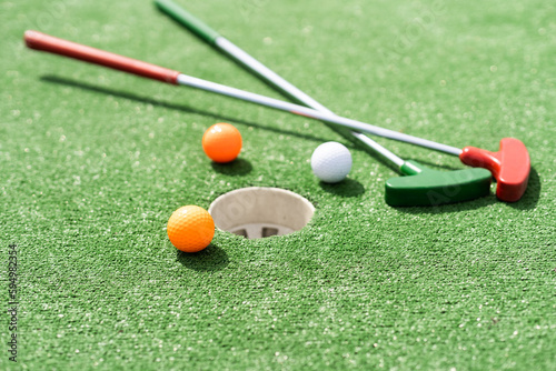 Close-up of miniature golf hole with bat and ball