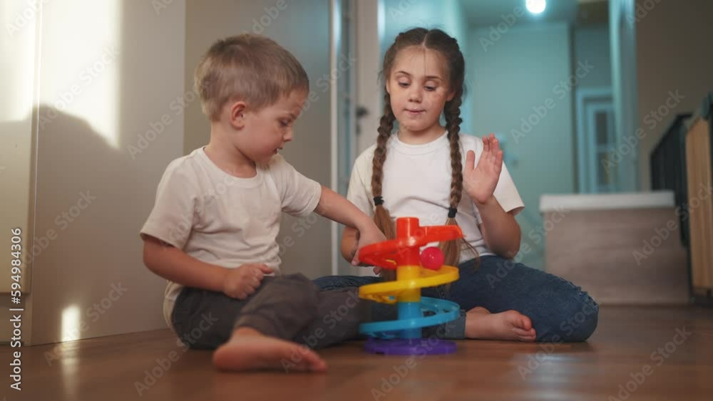 children baby play together toys in kindergarten. happy family preschool education indoor concept. baby boy and girl play toy roll a ball down a slide lifestyle on the floor rejoice in kindergarten children baby play together toys in kindergarten. happy family preschool education indoor concept. baby boy and girl play toy roll a ball down a slide lifestyle on the floor rejoice in kindergarten