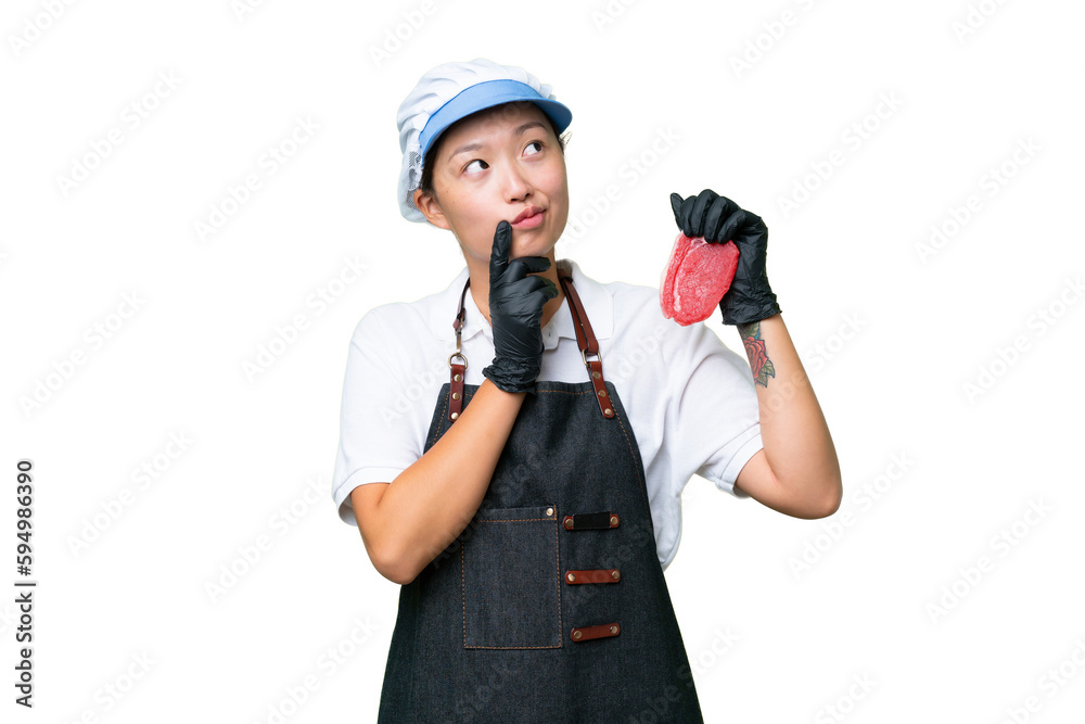 Young caucasian woman wearing an apron and serving fresh cut meat over isolated background having doubts while looking up Young caucasian woman wearing an apron and serving fresh cut meat over isolated background having doubts while looking up