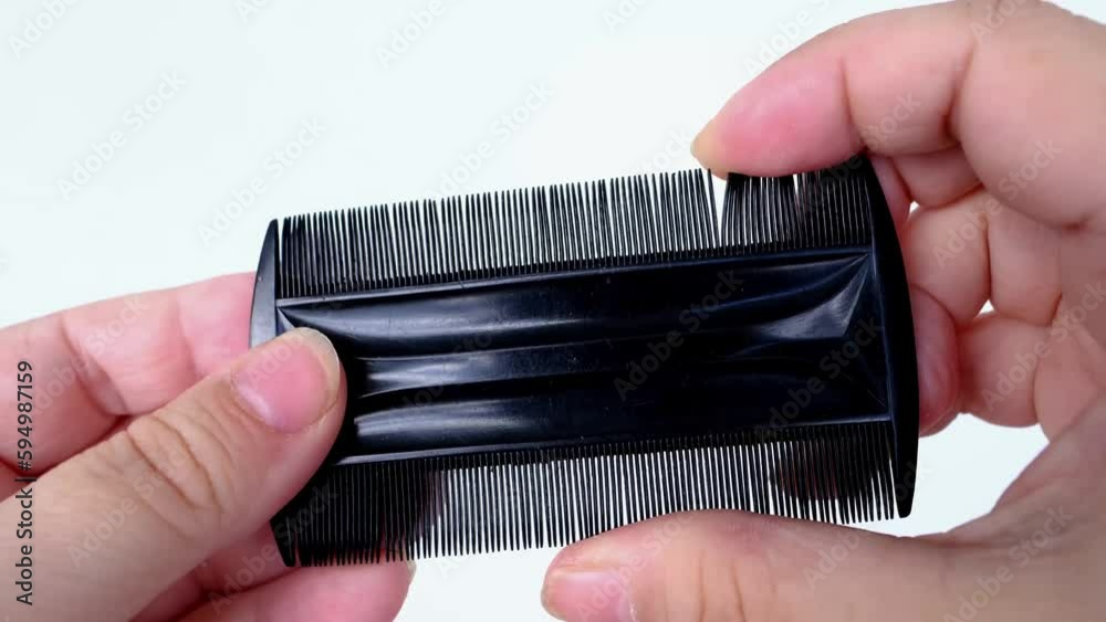 black plastic comb, fine comb, tool in female hands, used to comb out