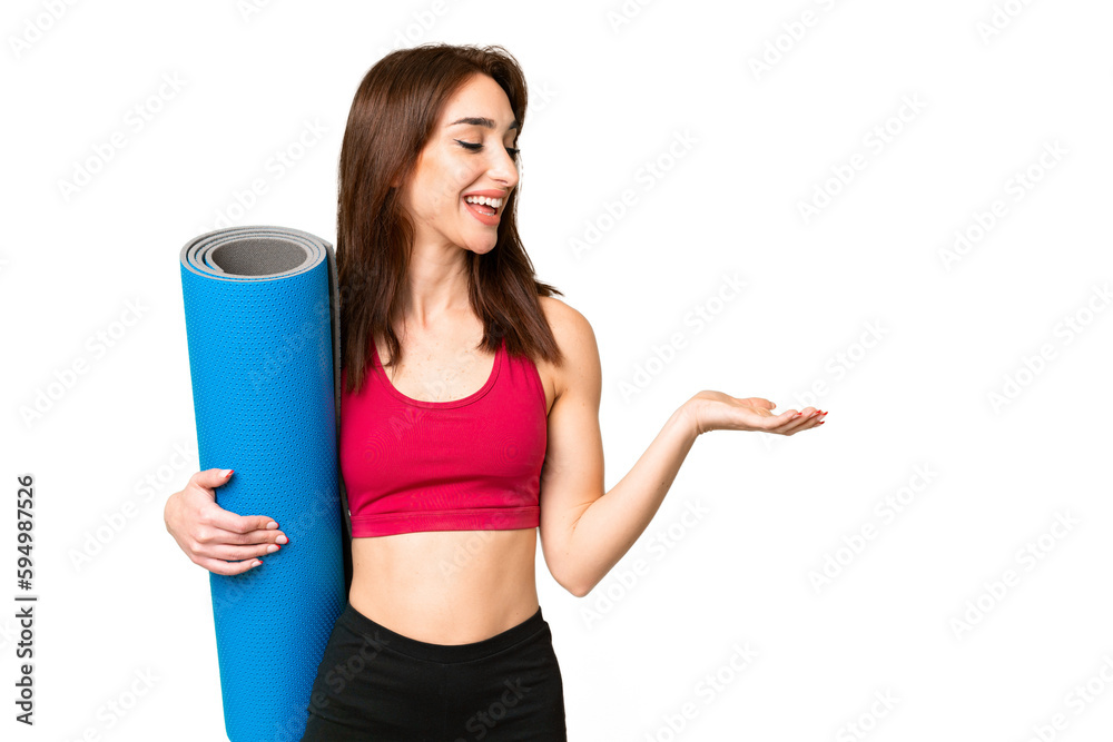 Young sport caucasian woman going to yoga classes while holding a mat over isolated chroma key background with surprise expression while looking side Young sport caucasian woman going to yoga classes while holding a mat over isolated chroma key background with surprise expression while looking side