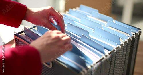The hands of a business woman sort through documents in a box, close-up. Organization of information on the topic photo