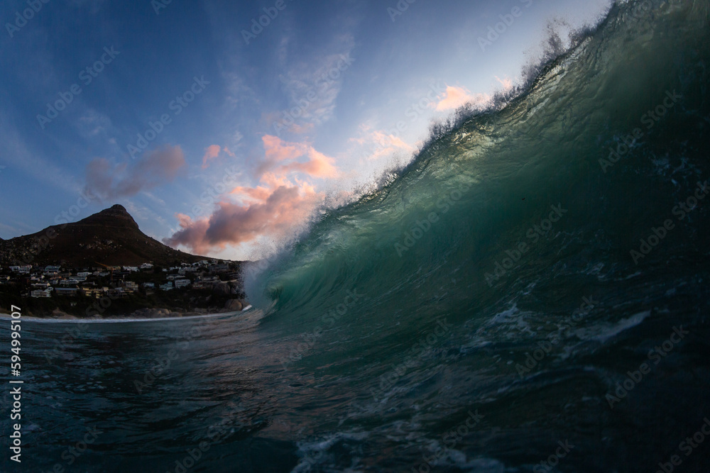 dramatic sunset with a huge wave breaking on a beach