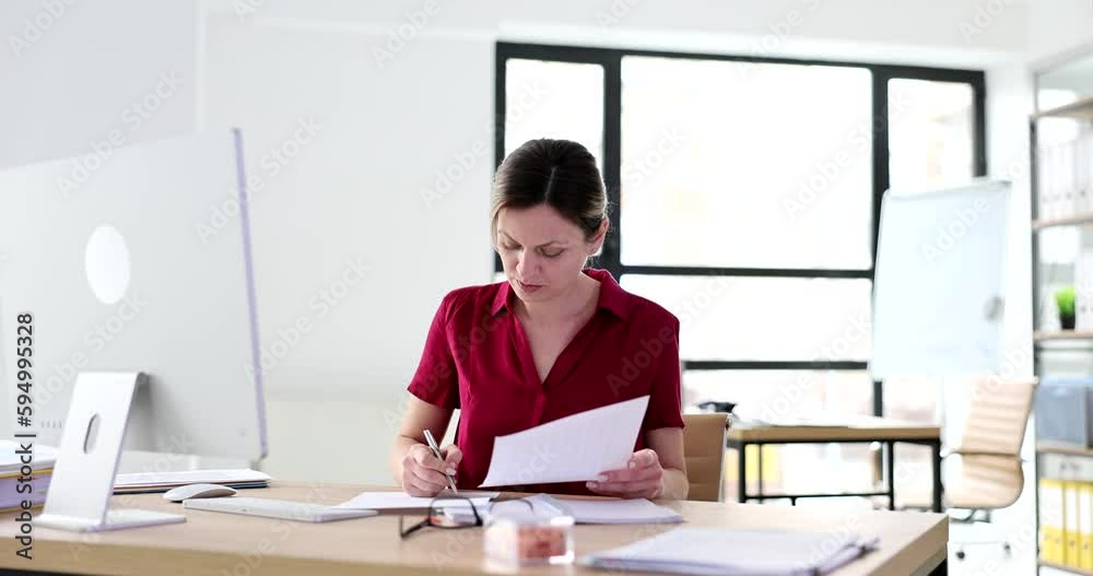 A business woman in the office watches a document and writes. Data reconnaissance online, slowmotion