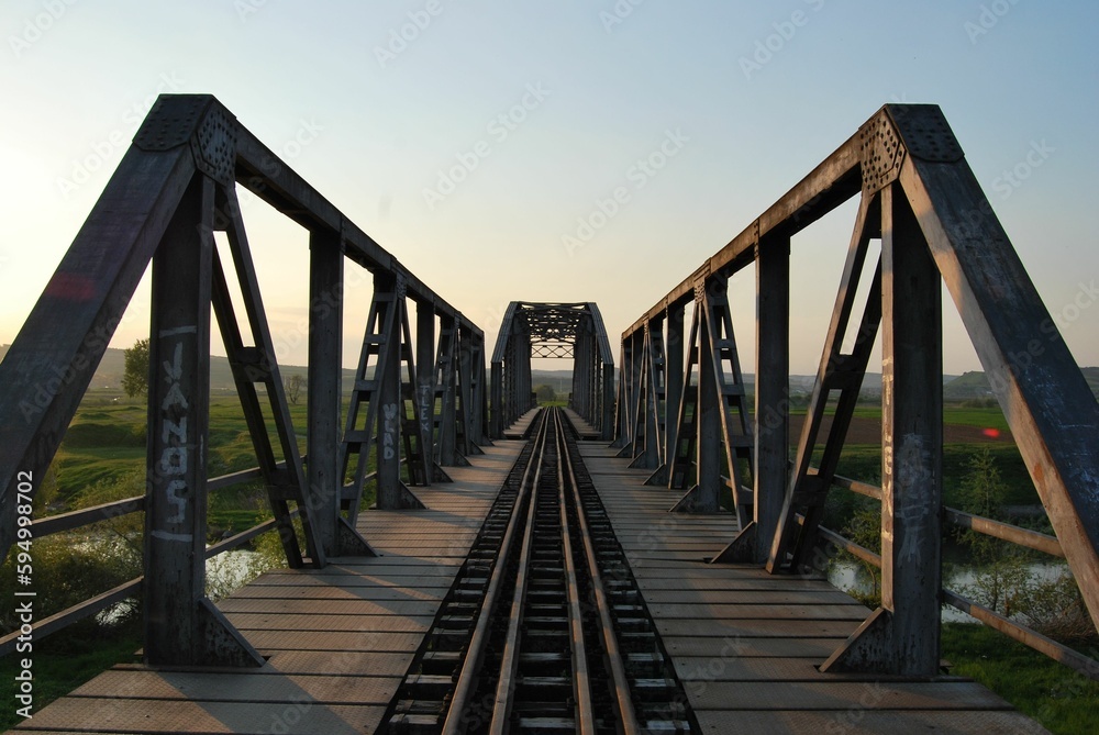 a bridge with rail tracks going across it and grass in the foreground a bridge with rail tracks going across it and grass in the foreground
