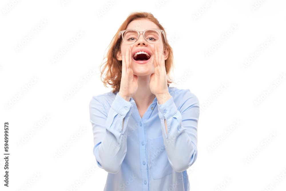 Portrait of redhead young woman screaming into her palms on white studio background. Important information, news concept Portrait of redhead young woman screaming into her palms on white studio background. Important information, news concept