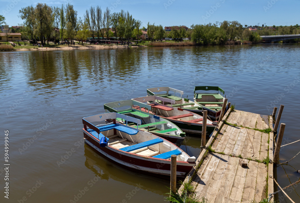 Coloridas barcas de madera amarradas en un pequeño pantalán en el río Duero a su paso por la ciudad de Zamora.