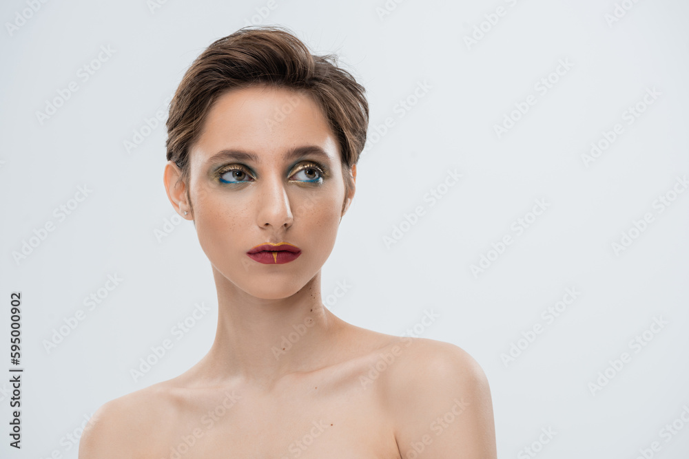 portrait of young woman with shiny makeup and short hair isolated on grey.