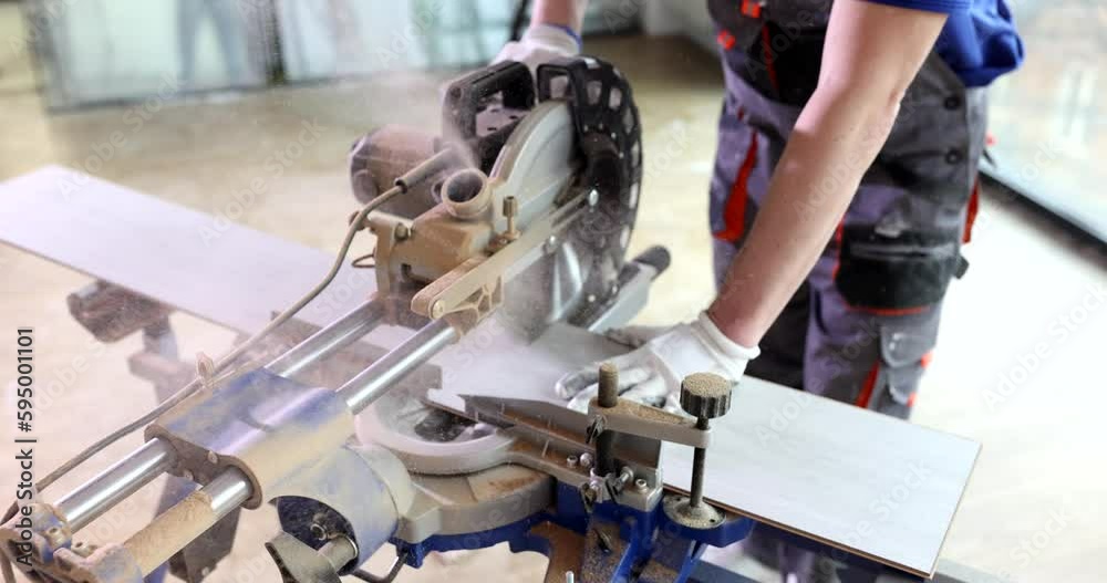 The master cuts the laminate on special electric equipment. Repair work in the office, carpenter workshop The master cuts the laminate on special electric equipment. Repair work in the office, carpenter workshop