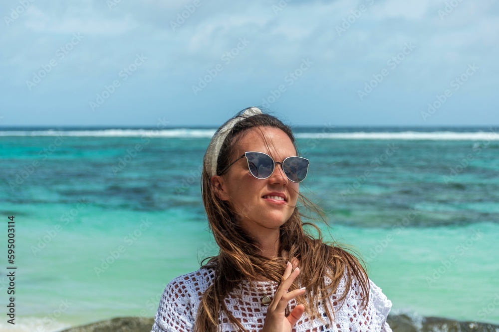 Portrait of beautiful happy woman posing on beach with amazing turquoise ocean in the back Portrait of beautiful happy woman posing on beach with amazing turquoise ocean in the back
