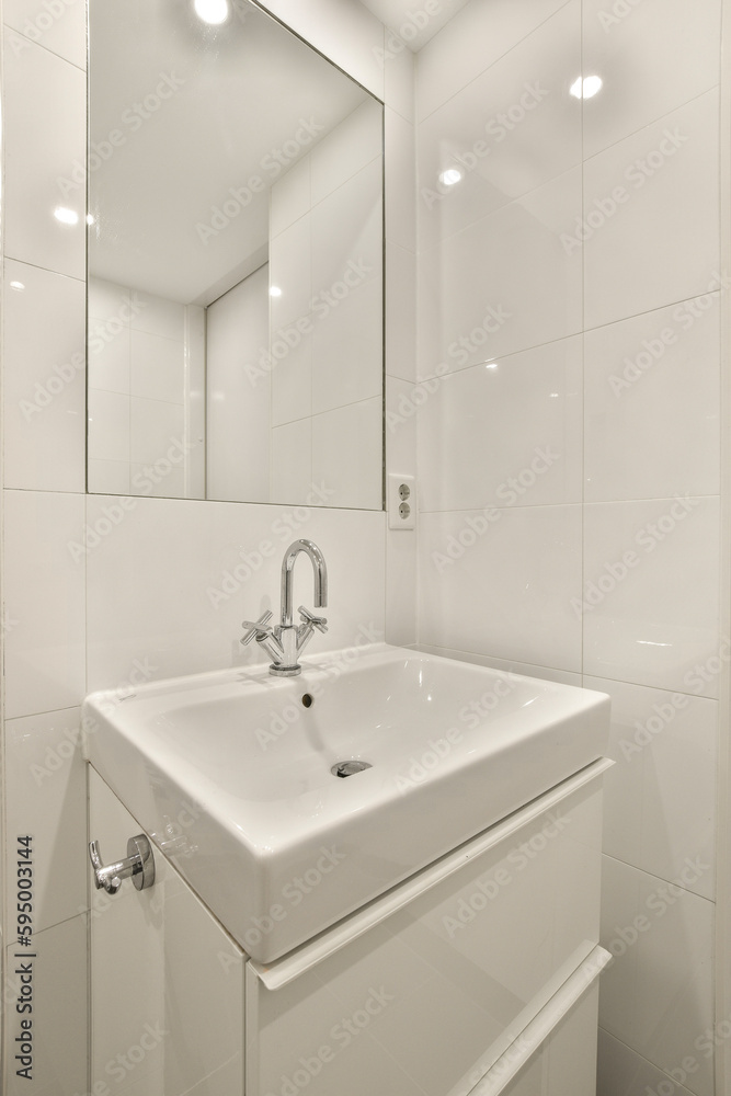 a white bathroom with a mirror above the sink and light fixtures on the wall in the room is very clean a white bathroom with a mirror above the sink and light fixtures on the wall in the room is very clean