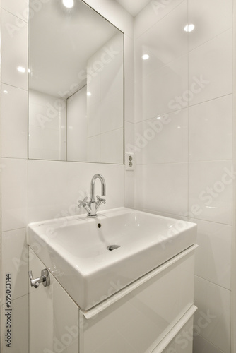 a white bathroom with a mirror above the sink and light fixtures on the wall in the room is very clean