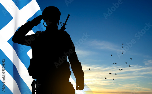 Silhouette of a saluting soldier with Greece flag against the sunset sky