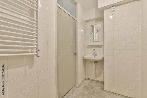 a small bathroom with white tiles on the walls and floor  along with a toilet in the center of the room