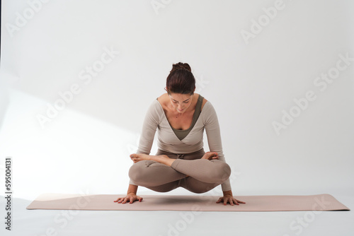 Slim woman doing Rooster pose during yoga photo