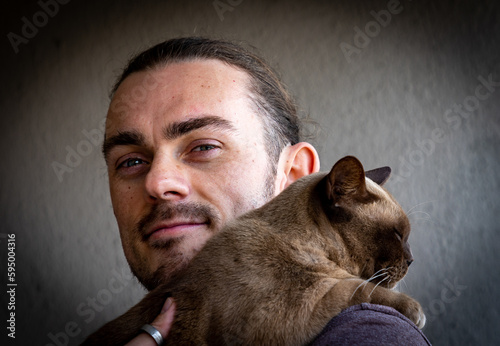 Portrait of a young man holding a Burmese cat