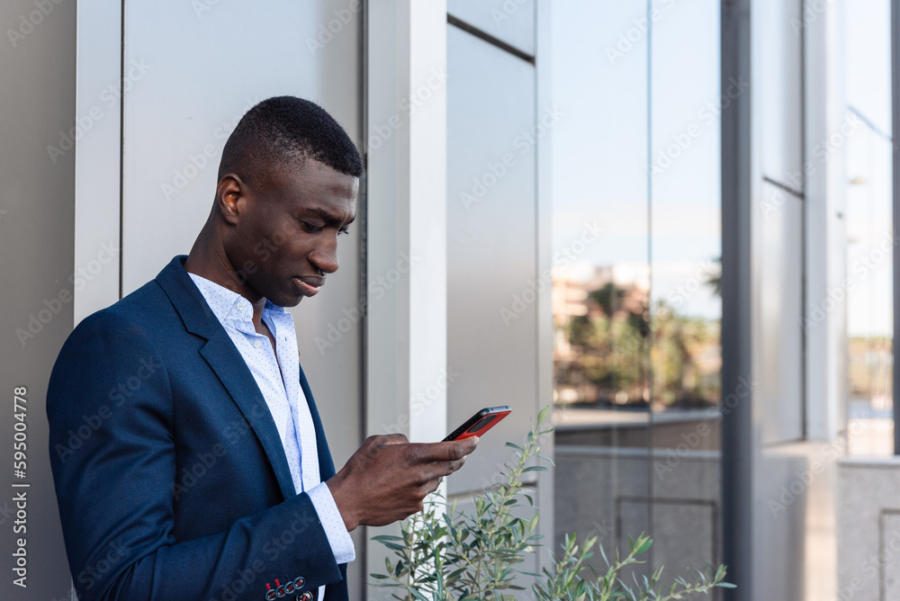Black man on mobile phone near modern building Black man on mobile phone near modern building