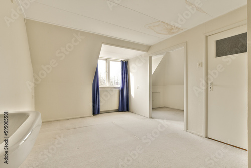 an empty room with white walls and blue drapes on the door is open to let in light from the window