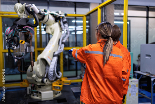 Wallpaper Mural Girl engineer commissioning operating programming and looking at robot machine in the factory Torontodigital.ca