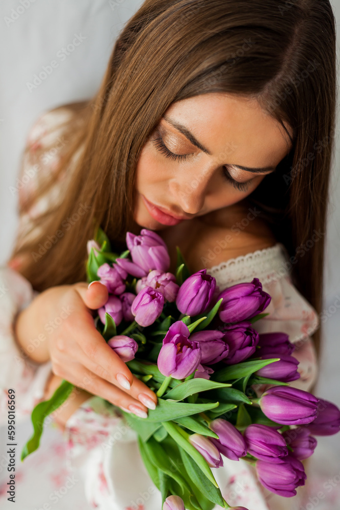 Portrait of sexy beautiful young woman with long hair. Model with a bouquet of lilac tulips on white. Spring. Holidays. Portrait of sexy beautiful young woman with long hair. Model with a bouquet of lilac tulips on white. Spring. Holidays.