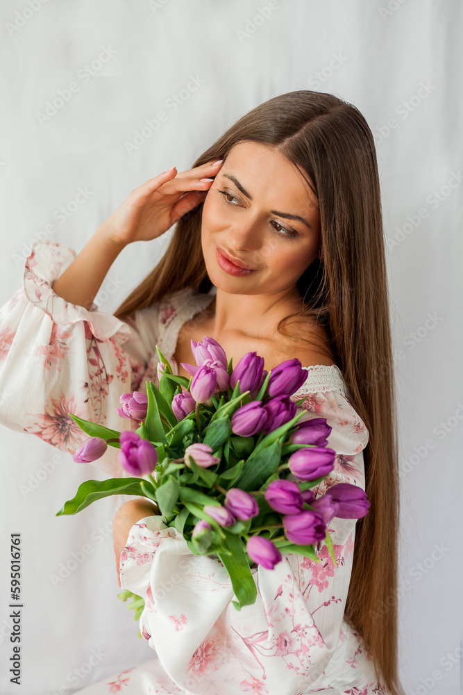 Portrait of sexy beautiful young woman with long hair. Model with a bouquet of lilac tulips on white. Spring. Holidays. Portrait of sexy beautiful young woman with long hair. Model with a bouquet of lilac tulips on white. Spring. Holidays.